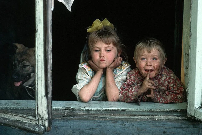 Ảnh 1: Two dirty-faced children look out of a window in a coal mining and steel production area in Siberia during a period of widespread economic hardship in the Soviet Union.